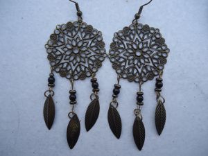 Ces boucles d'oreilles sont composées d'un connecteur rond estampe filigranée fleur, métal bronze 35 mm, de perles rocailles bronzes et turquoises/noires et de plumes bronzes. Elles mesurent environ 6 cm. 