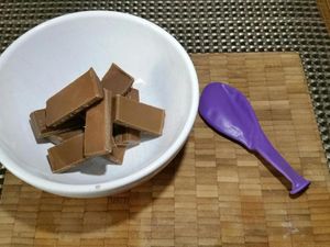 2 - Faire fondre le chocolat avec précaution au micro-ondes dans un bol. Laisser légèrement tiédir. Gonfler un ballon à la taille voulue et en tremper la base délicatement dans le bol de chocolat. Poser un petit disque de chocolat sur du papier sulfurisé et poser la base du ballon enrobé de chocolat sur ce petit disque. Laisser refroidir complètement. Décoller délicatement la coupelle du papier sulfurisé avec un couteau. Puis appuyer doucement sur le ballon sur tout le tour de la coupelle pour dégager le chocolat. Faire ensuite une légère entaille dans le haut du ballon (près du noeud) pour qu'il se dégonfle lentement. Votre coupelle est prête à être garnie.