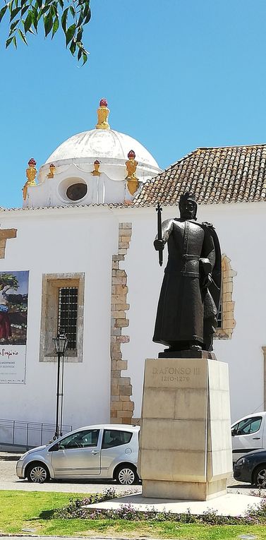 Porte de la vieille ville, statue du roi Alphonse III, scène de libération et cigognes.