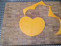 2 - Découper une forme en coeur dans du papier sulfurisé, reporter ce gabarit sur la tranche de mimolette et découper. Dans la 2ème tranche de poulet réaliser un disque avec un emporte-pièce rond qui servira pour la tête du chien. Faire les yeux du chien dans les chutes de la tranche de mimolette. Couper une olive noire dénoyautée en fine rondelle et en petits morceaux courbes pour les yeux, la bouche puis tailler de petits éclats noirs pour les moustaches. Une rondelle de cornichon et le bout sans trou de l'olive noire serviront à réaliser la truffe. Découper dans la tomate un morceau en forme de langue, 2 bandes rectangulaires dans la 2ème tranche de poulet pour les pattes et deux demi-cercles pour les oreilles.