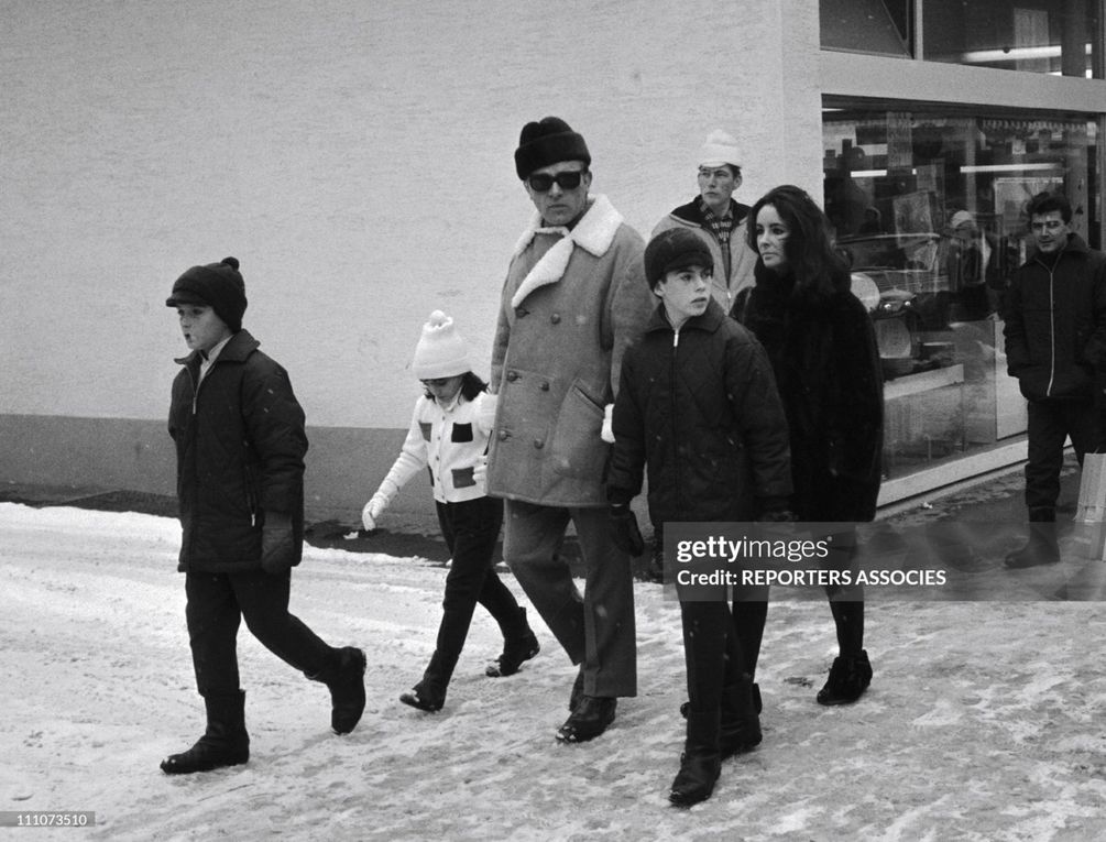 1964 December 22, Gstaad, Family walk in the town centre, with Michael Jr. and Christopher Wilding, Elizabeth Taylor and Richard Burton holding Liza Todd's hand. 