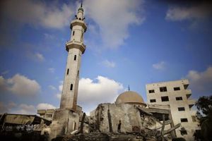 A Palestinian stands atop the remains of a mosque, which was hit in an Israeli air strike