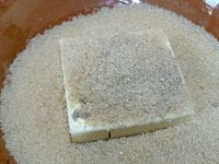 4 - Passer à la préparation du crumble. Dans un récipient, mélanger le beurre froid, le sucre roux, le sucre vanillé, la farine, la cannelle et la noix de coco. Malaxer du bout des doigts pour obtenir un sable grossier. 
