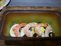 4 - Dans des moules en silicone (sinon penser à les beurrer) alterner successivement en couches :  pommes de terre, échalotes et champignons, oeufs, olives, crevettes et recommencer jusqu'à remplir au 3/4 les moules en terminant par une rangée de pommes de terre. Pour finir, verser dans les moules le mélange oeuf/crème fraîche qui doit bien recouvrir les pommes de terre. Parsemer le reste d'emmental râpé 
