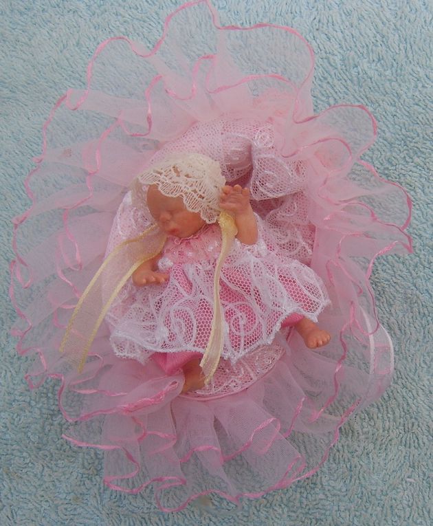 Ma deuxième Mini sculpture bébé ooak en polymère, réalisée sans moules. Les premières images montrent la sculpture avant que je la ponce dans le but de refaire la teinte de la peau. Vêtements et Moïse en satin, Organza et dentelle de Calais.