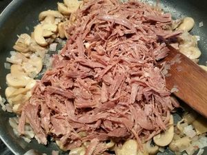 2 - Verser 2 cuil. à soupe de graisse de canard dans une poêle. Y faire revenir les échalotes jusqu'à ce qu'elles soient translucides, puis les champignons. Mélanger et laisser cuire 2 à 3 mn,   Rajouter l'effiloché de canard, remuer et finir par le madère. Le laisser réduire et s'évaporer. Finir en assaisonnant avec le persil, le poivre et une légère pincée de sel. Bien mélanger et réserver au chaud. Mettre le beurre dans une jatte, avec les pommes de terre cuites, pelées et coupées en morceaux. Commencer à écraser puis rajouter la crème fraîche. Si la purée est trop épaisse rajouter un peu d'eau de cuisson des pommes de terre pour ajuster la consistance à votre goût (elle doit se tenir). Bien écraser jusqu'à obtenir une purée homogène, saler et poivrer. 