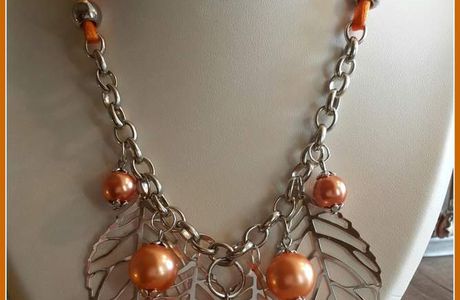 Collier sur chaine , perles oranges et plumes argentées.